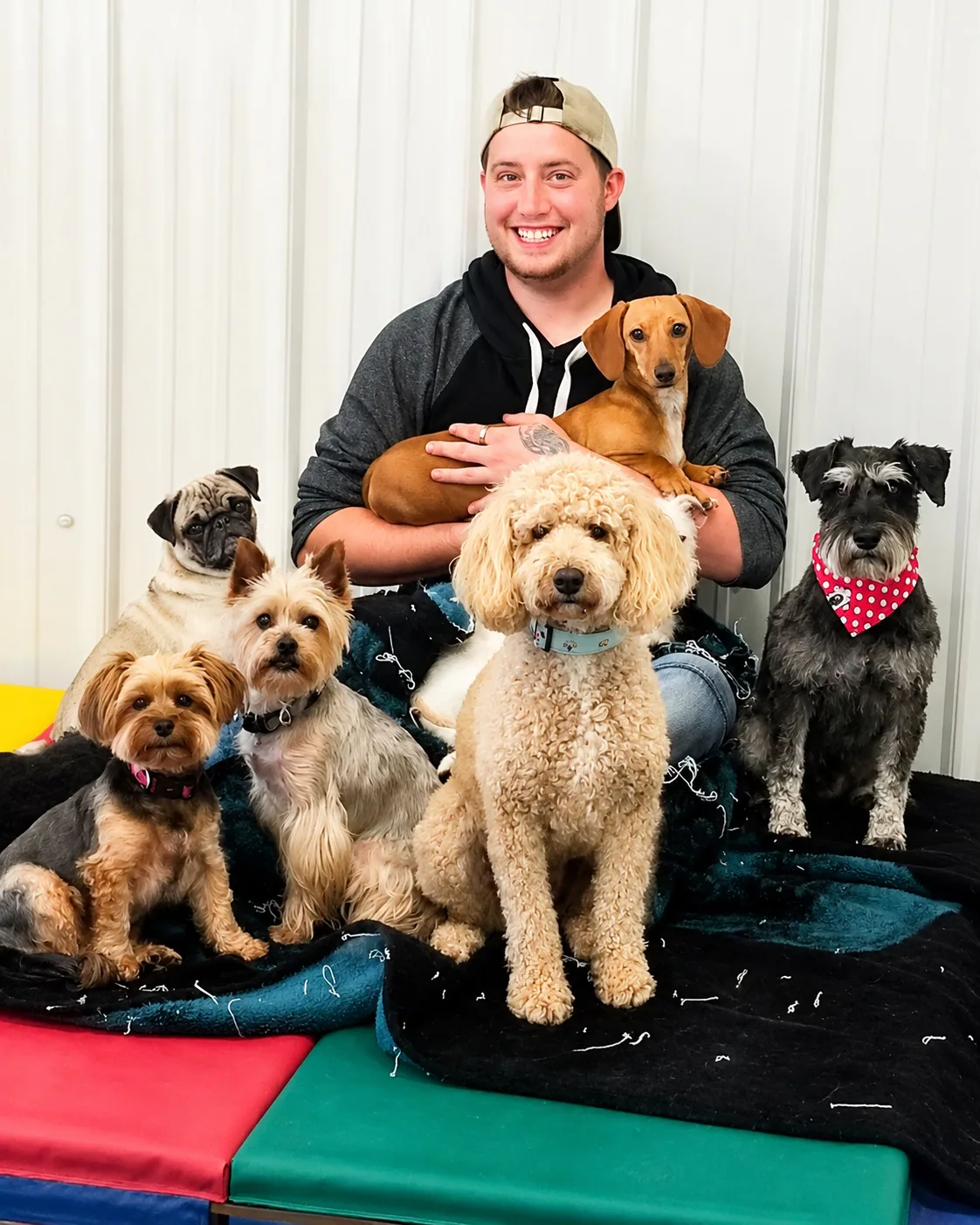 A smiling Jollytails team member surrounded by a group of dogs