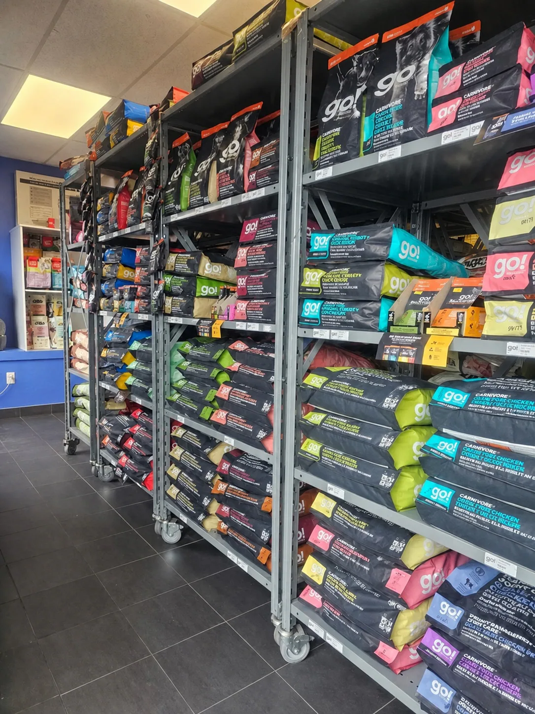 Shelves stocked with bags of dog food inside a Jollytails pet store