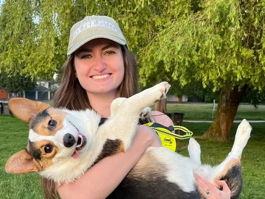 Amy from the Jollytails Burnside daycare team holding a corgi outdoors
