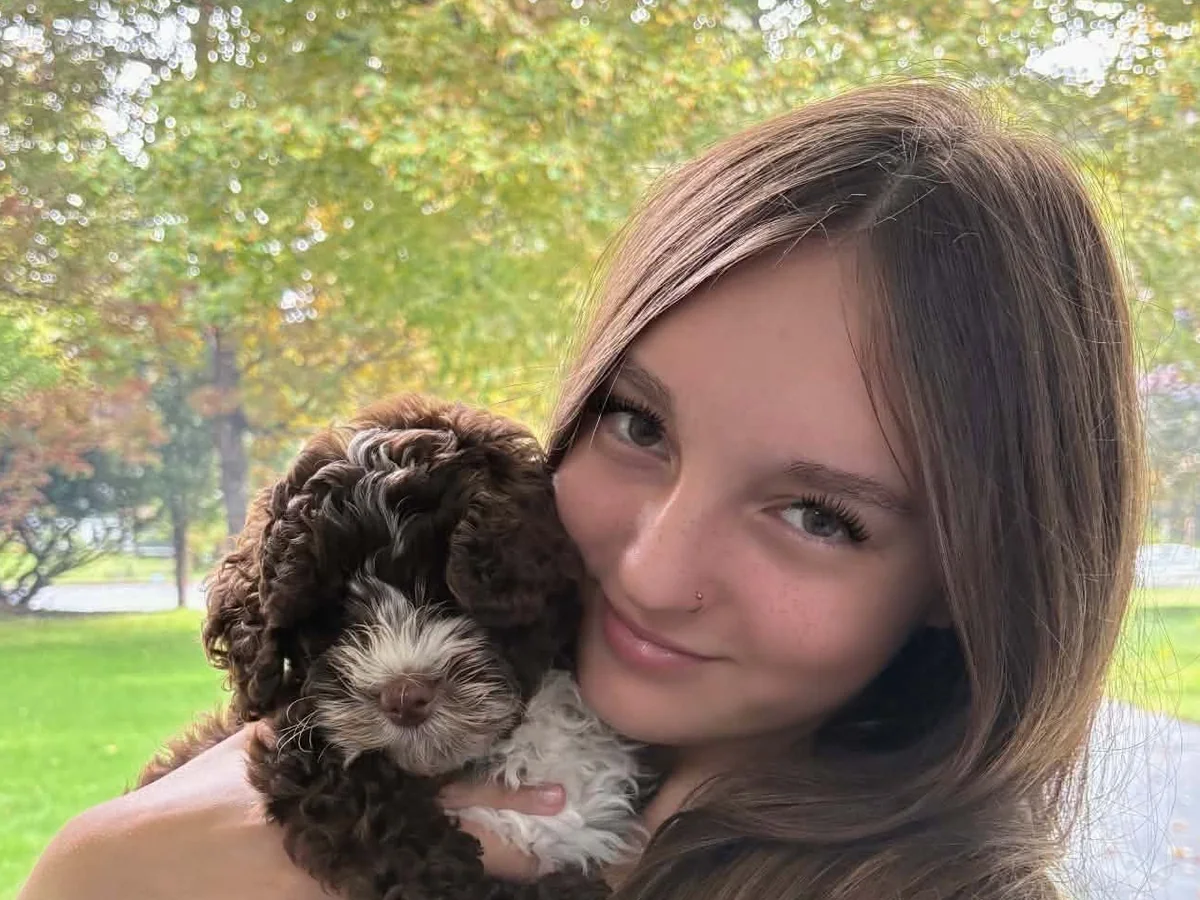 Charlotte from the Jollytails Burnside daycare team holding a brown-and-white puppy