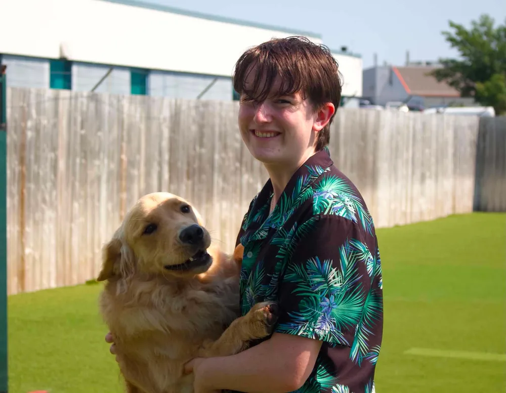 Edwin from the Jollytails Lady Hammond daycare team with a dog